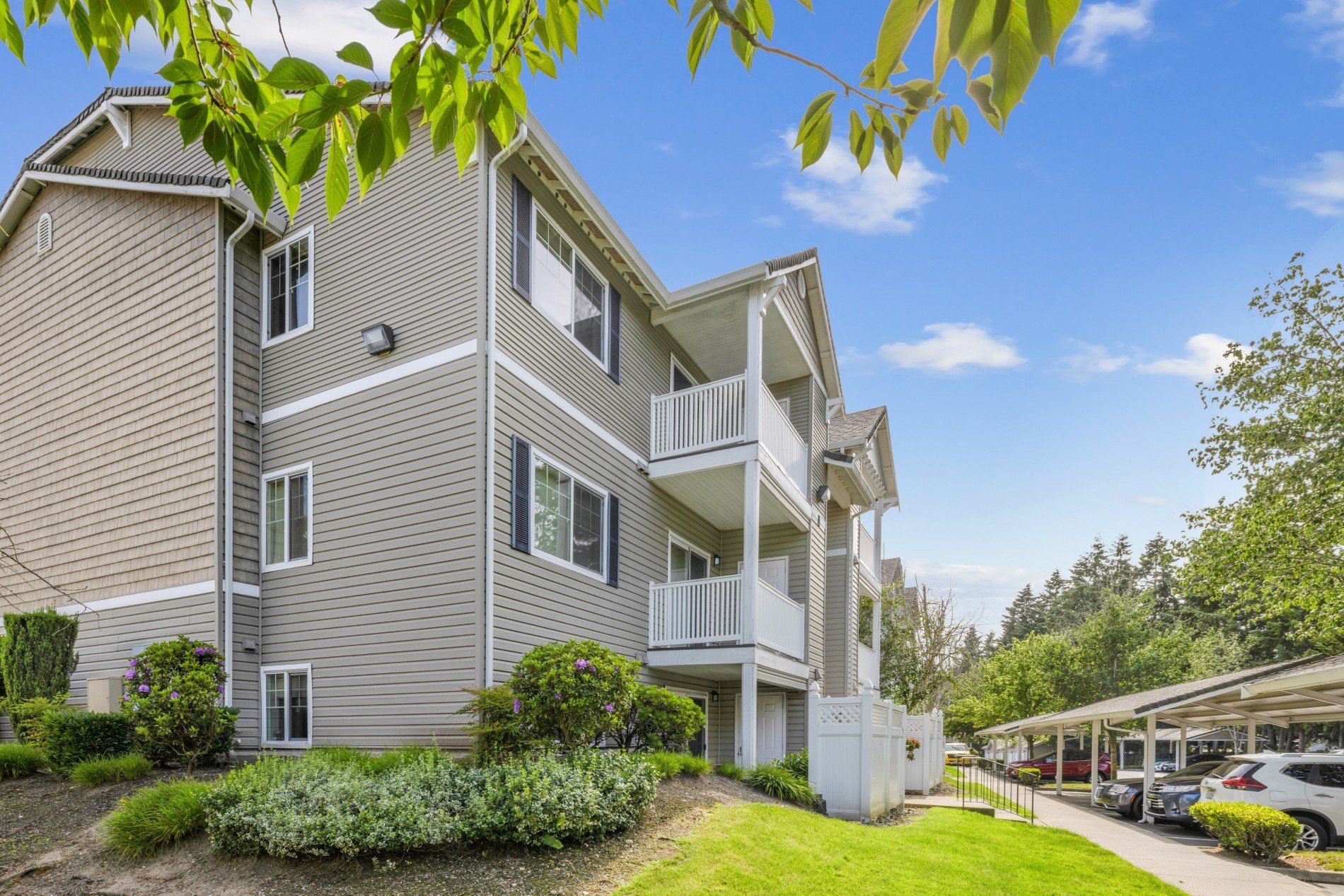 A 3 story apartment building with a lush lawn and parking lot in front at Abbey Rowe Apartments in Olympia, WA